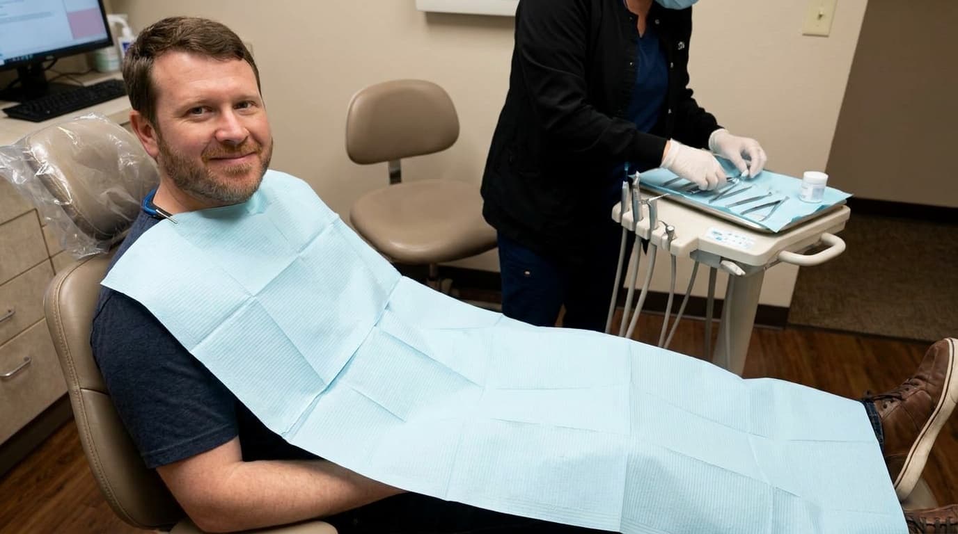 Sam sits calmly in a dentist chair wearing a protective dental bib.