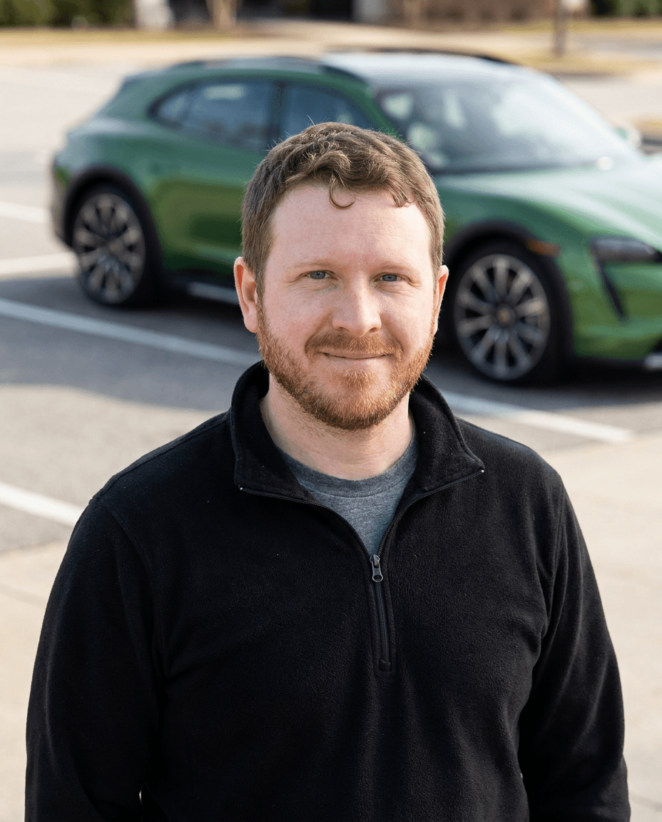 Sam standing beside his green electric wagon in a parking lot.