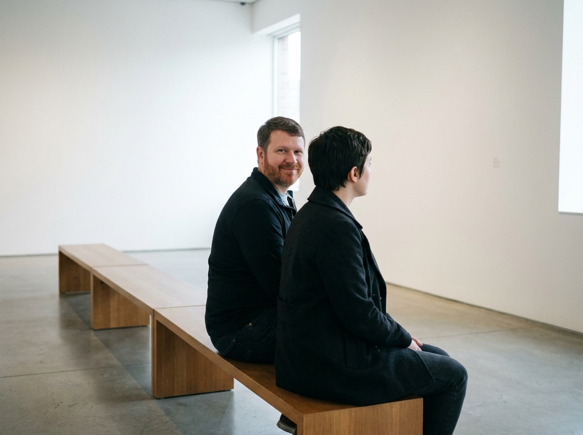 Sam calmly smiling while sitting too close to a stranger on a museum bench.