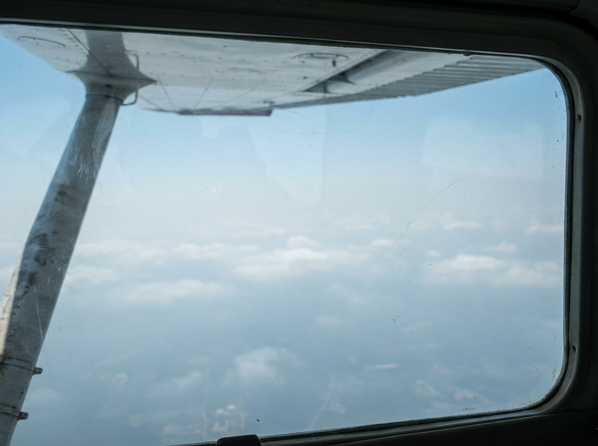 Wing edge and pale sky from a small airplane.